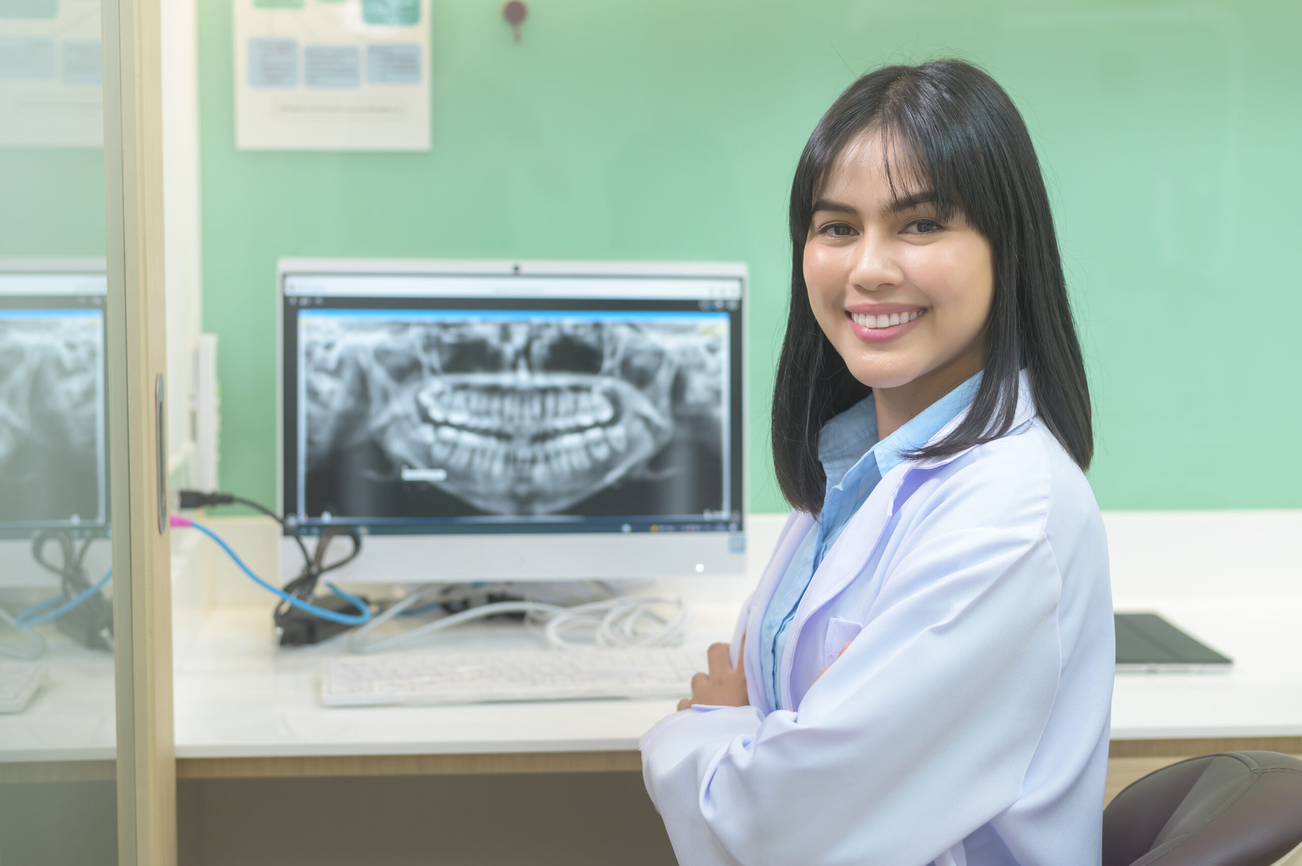 A female dentist working with teeth x-ray on laptop in dental clinic